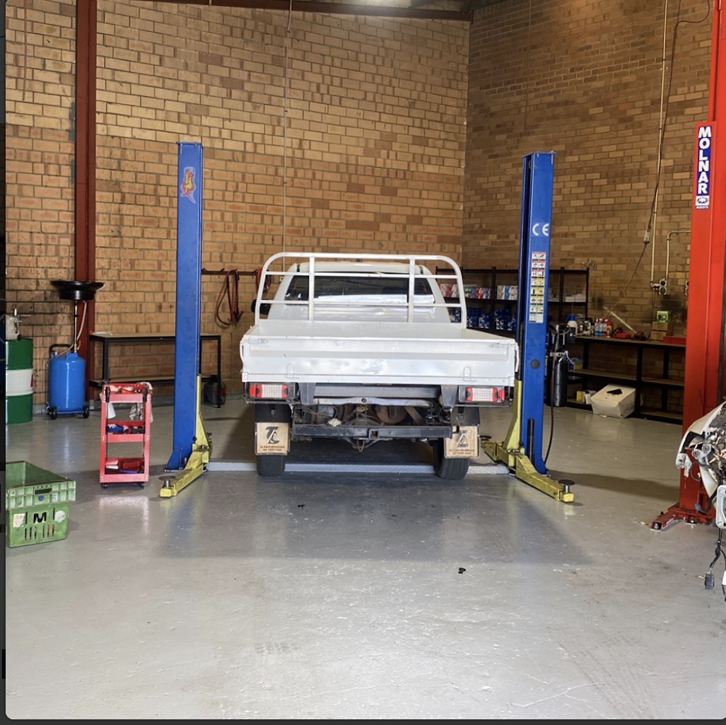 A flat-tray ute on a hoist in the second bay